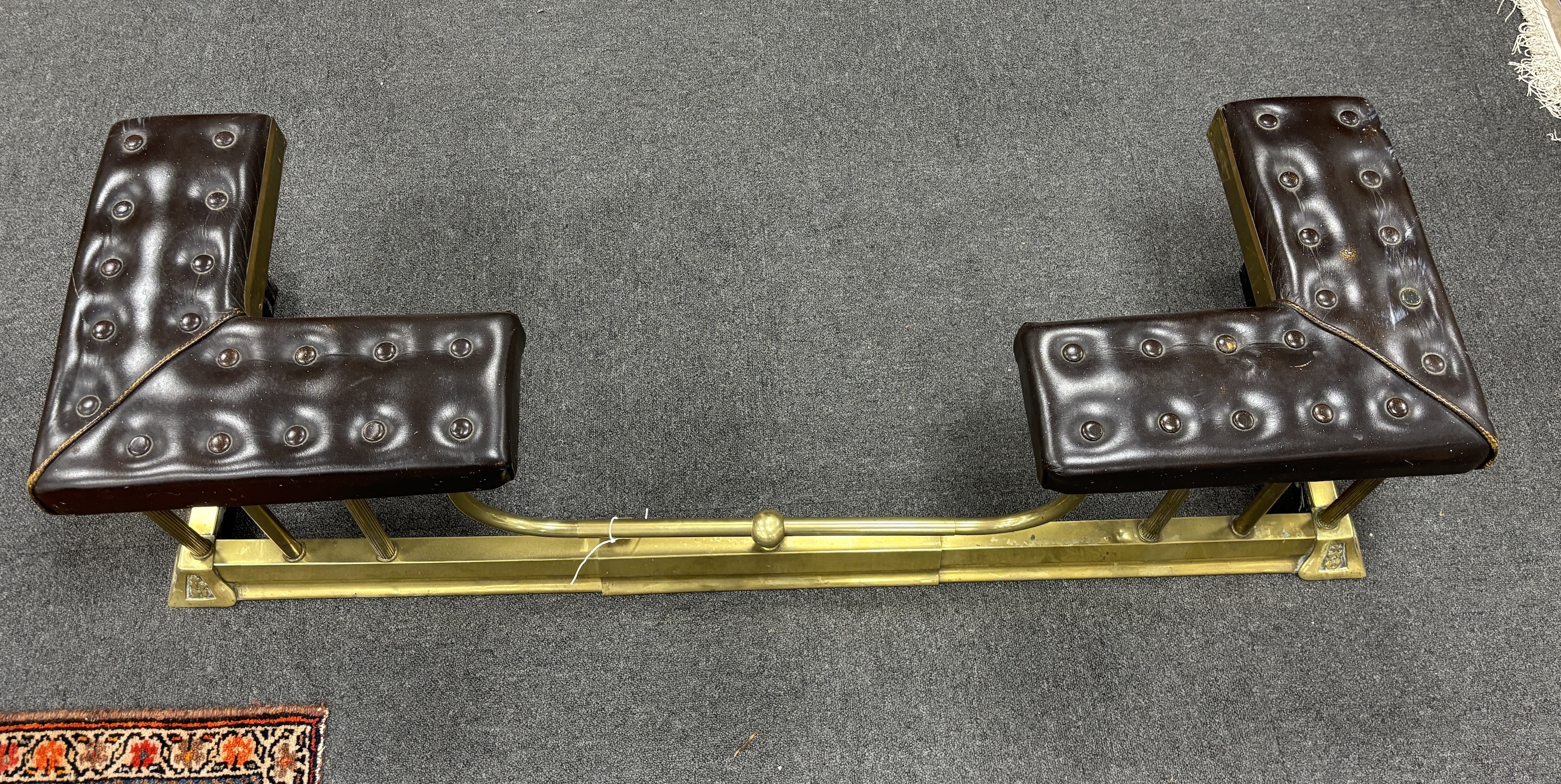 An early 20th century brass and buttoned brown leather telescopic club fender, minimum width 132cm, depth 40cm, height 36cm
